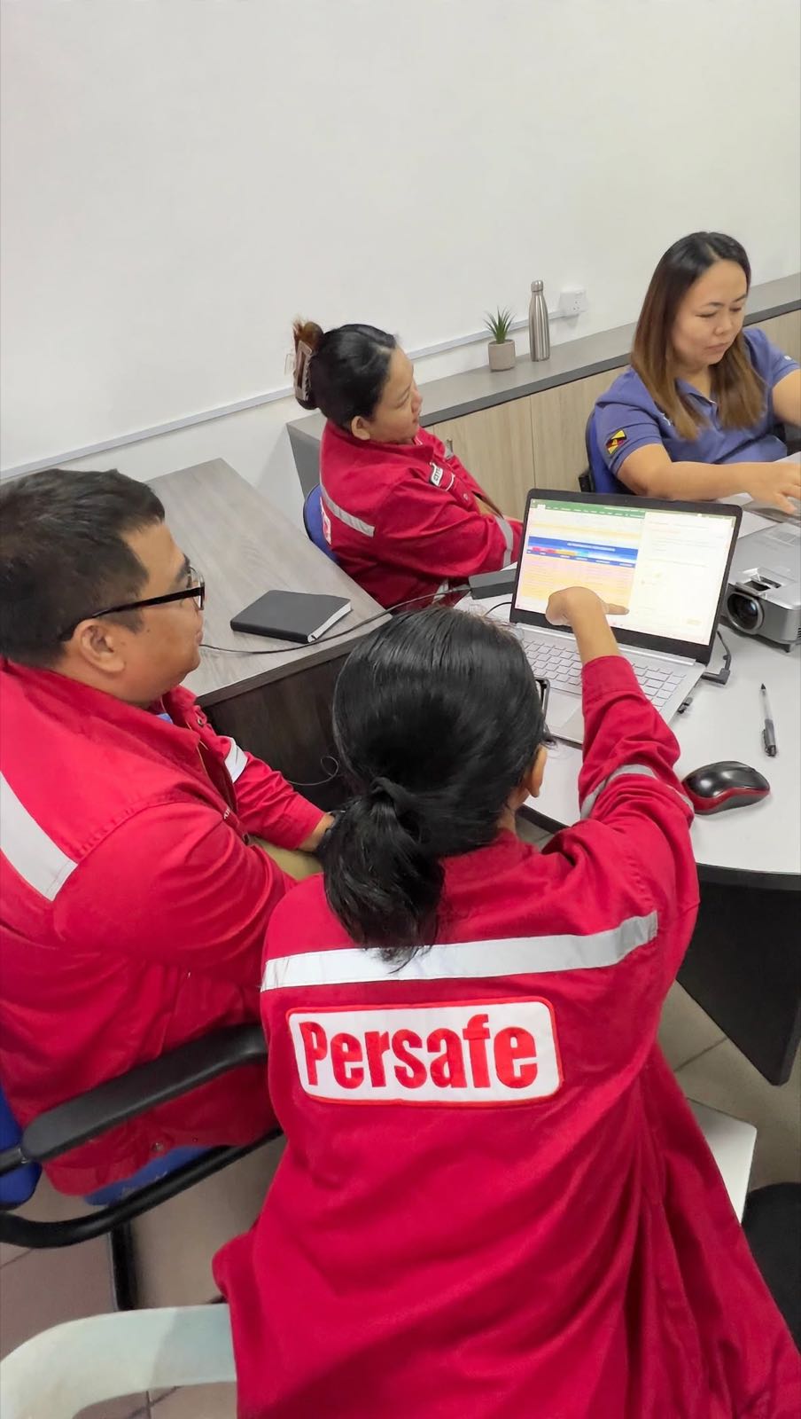 Persafe staff working together on a spreadsheet on a laptop